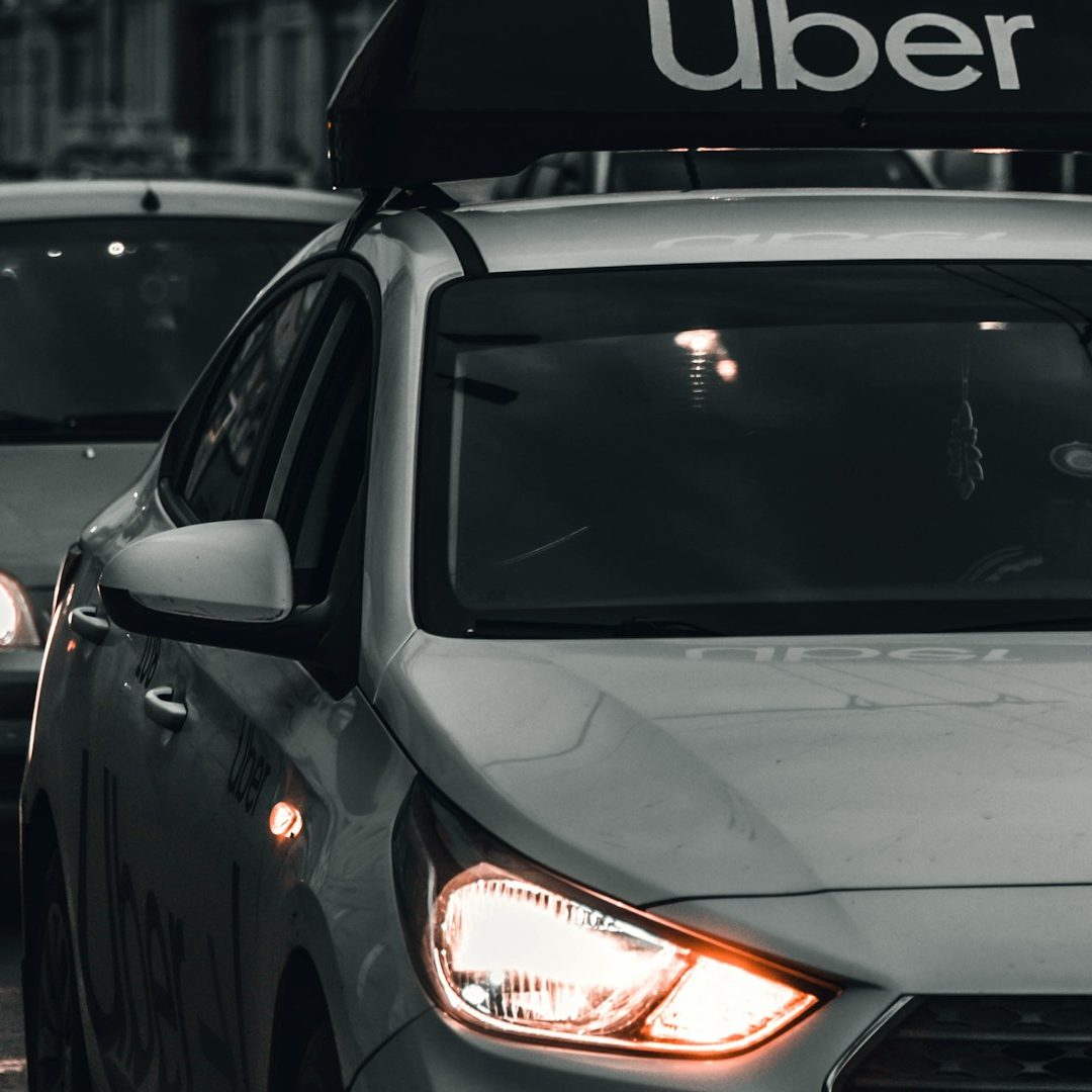 A close-up of an Uber vehicle with the logo on the rooftop, parked in traffic.